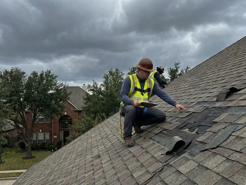 Roofing professional assessing storm damage on residential roof